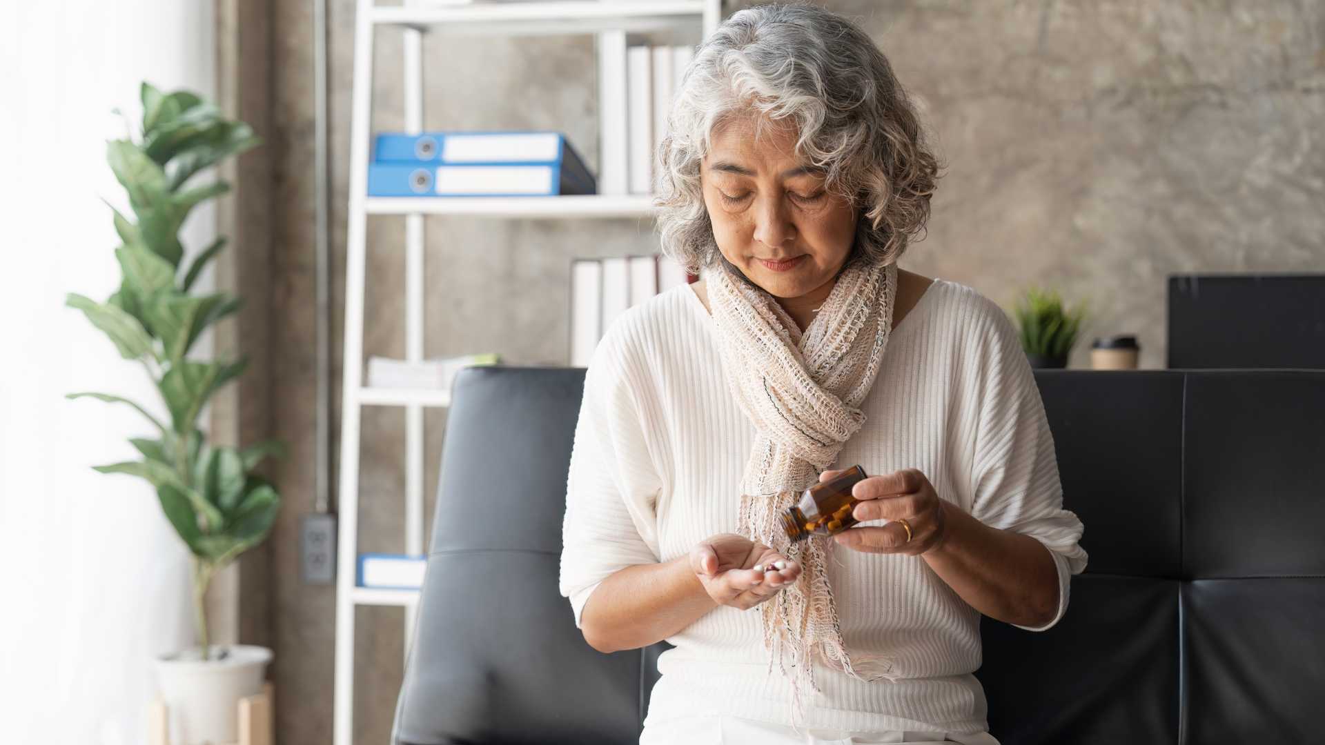Older woman pouring pills into hand