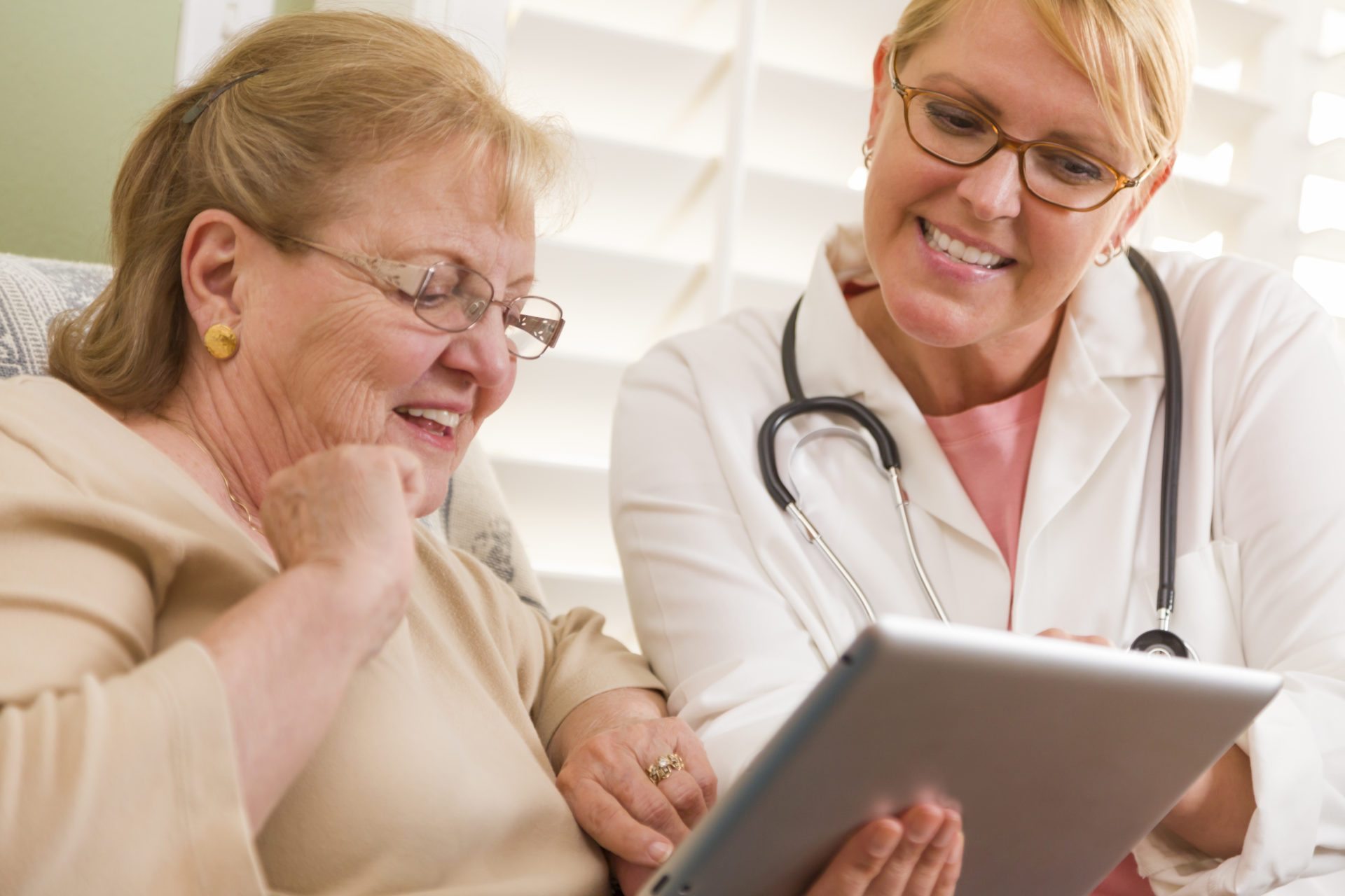 Doctor or Nurse Talking to Senior Woman with Touch Pad Computer.