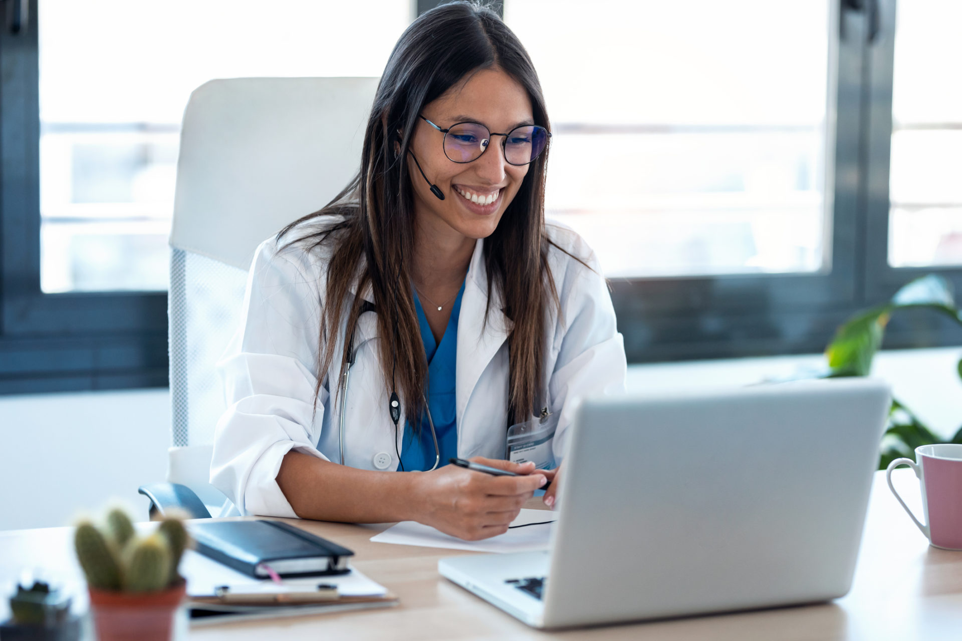 Shot of female doctor talking with colleagues through a video call with a laptop in the consultation.