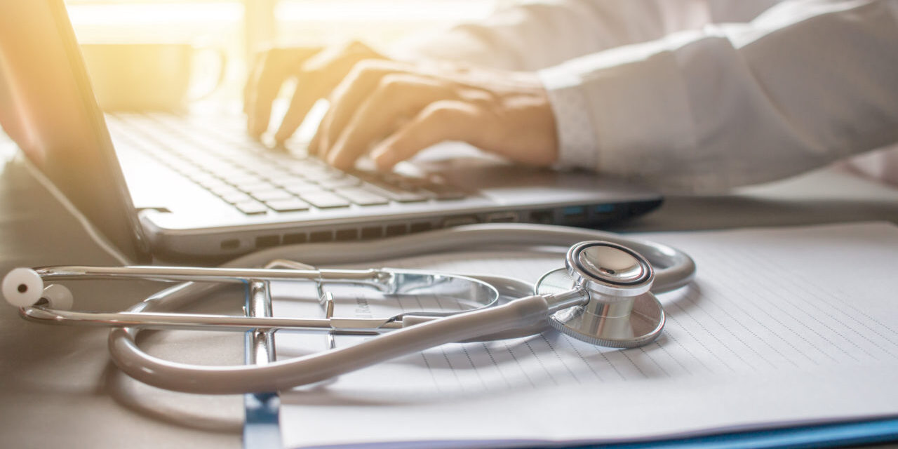 Stethoscope on prescription clipboard and Doctor working an Laptop on desk in hospital,